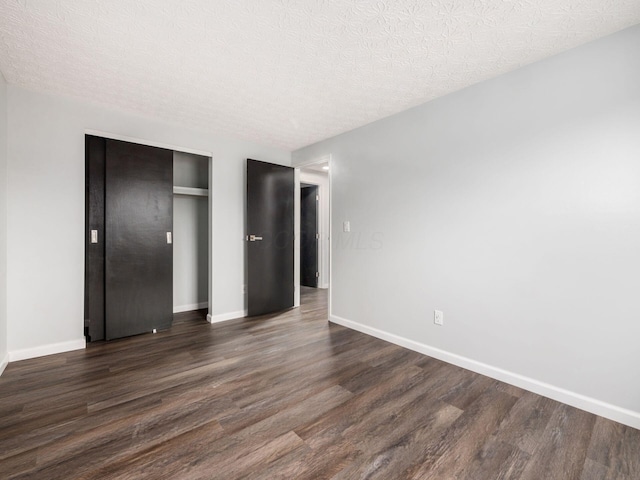 unfurnished bedroom featuring a textured ceiling, a closet, and dark wood-type flooring