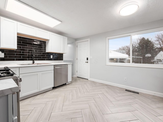 kitchen with dishwasher, a textured ceiling, white cabinets, and sink