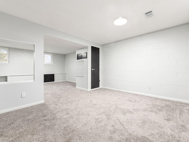 basement with carpet, a healthy amount of sunlight, and brick wall