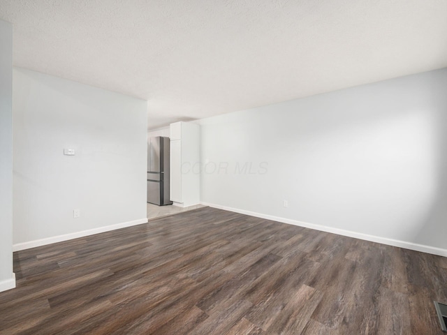 empty room with a textured ceiling and dark hardwood / wood-style floors