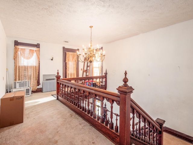 hallway featuring light colored carpet, radiator heating unit, a textured ceiling, and a chandelier