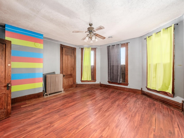 empty room with radiator heating unit, a textured ceiling, hardwood / wood-style flooring, and ceiling fan