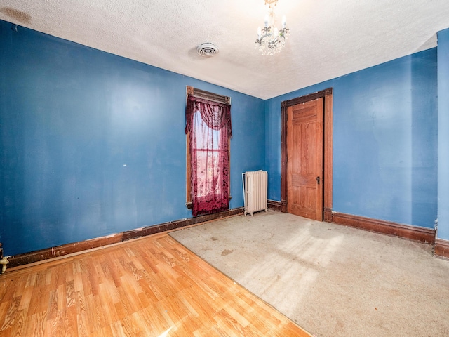 unfurnished room featuring hardwood / wood-style flooring, a textured ceiling, and radiator