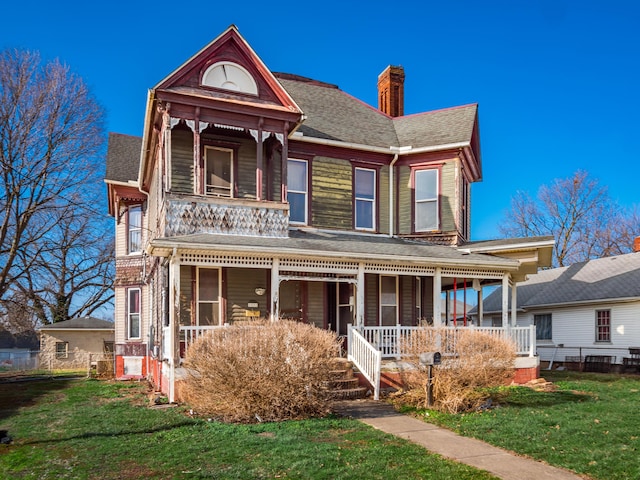 victorian-style house featuring a porch and a front yard