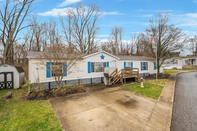 manufactured / mobile home featuring a front yard, a deck, and a storage shed