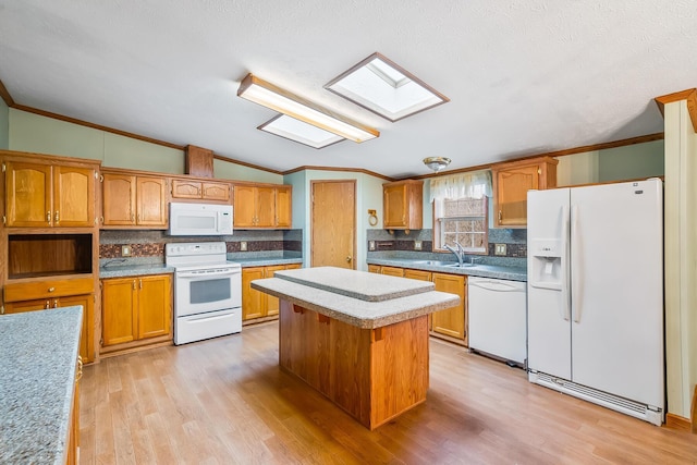 kitchen with sink, white appliances, ornamental molding, and vaulted ceiling with skylight