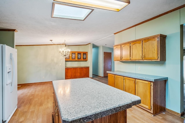 kitchen featuring white fridge with ice dispenser, a center island, a notable chandelier, and ornamental molding