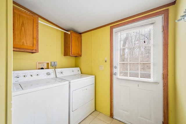 laundry room featuring washer and clothes dryer, cabinets, and light tile patterned floors