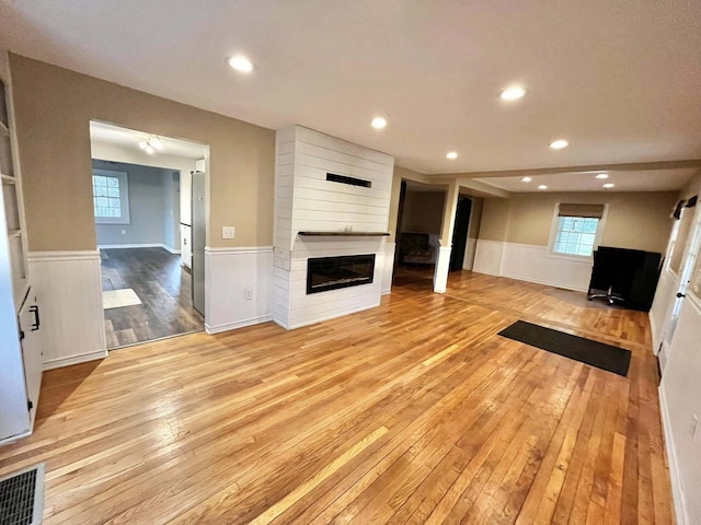 unfurnished living room featuring a large fireplace and light wood-type flooring