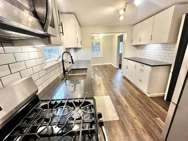 kitchen featuring dark hardwood / wood-style flooring, refrigerator, tasteful backsplash, sink, and white cabinets