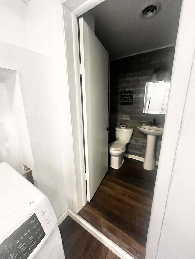 bathroom featuring hardwood / wood-style floors, toilet, sink, and washer / clothes dryer