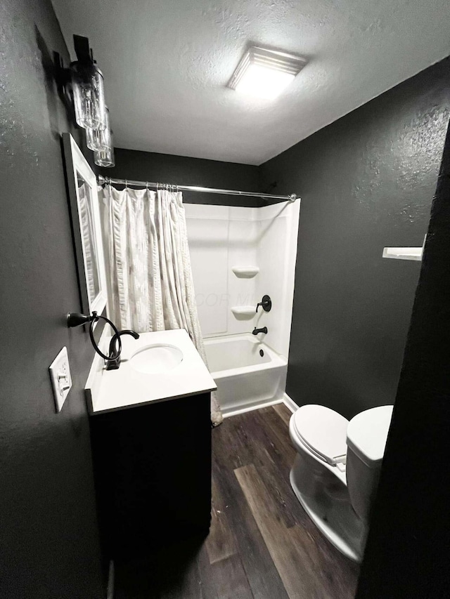 full bathroom featuring hardwood / wood-style floors, vanity, shower / bath combination with curtain, toilet, and a textured ceiling