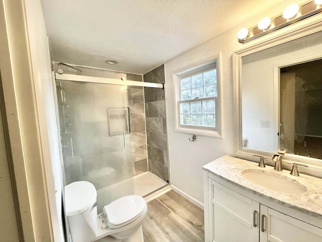 bathroom featuring walk in shower, hardwood / wood-style floors, a textured ceiling, toilet, and vanity