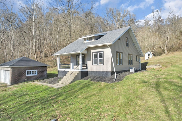 exterior space with covered porch, a garage, an outbuilding, and a front lawn