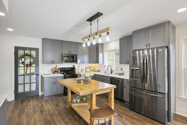 kitchen with sink, decorative backsplash, gray cabinets, decorative light fixtures, and stainless steel appliances