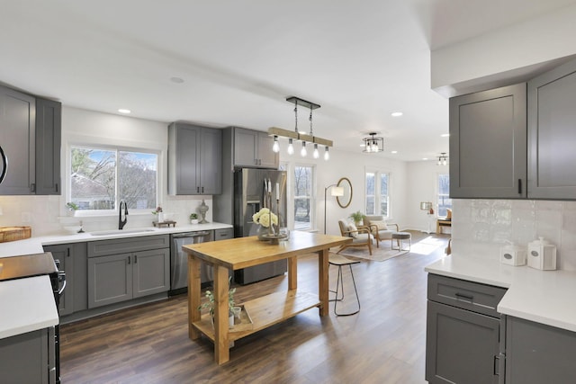 kitchen featuring gray cabinetry, backsplash, sink, appliances with stainless steel finishes, and decorative light fixtures