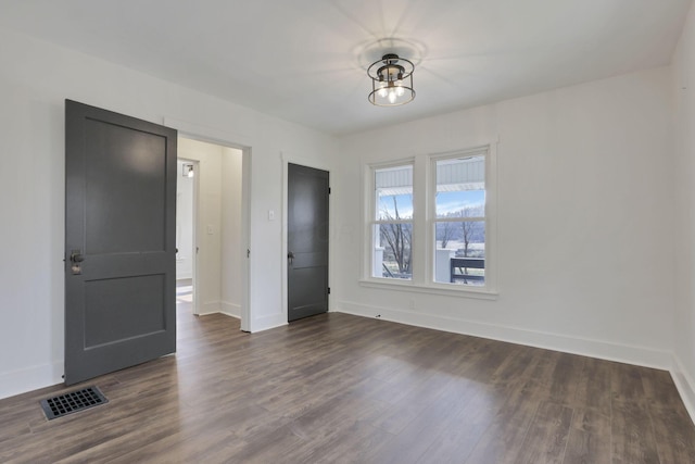 unfurnished room with a notable chandelier and dark hardwood / wood-style floors