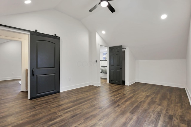 bonus room featuring ceiling fan, dark hardwood / wood-style floors, a barn door, and lofted ceiling