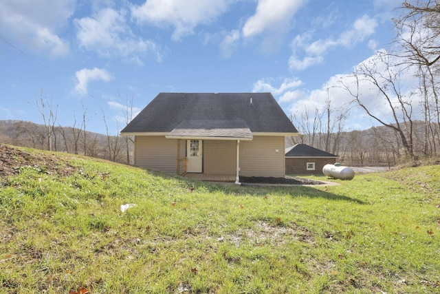 back of house with a mountain view and a lawn