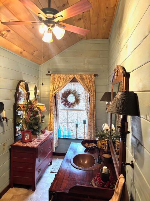 bathroom with vaulted ceiling, ceiling fan, wooden ceiling, and wood walls