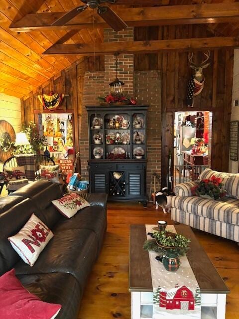 living room with lofted ceiling with beams, hardwood / wood-style flooring, wood ceiling, and wood walls