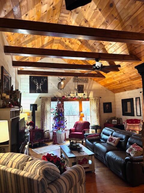 living room featuring a wood stove, vaulted ceiling with beams, wood-type flooring, wooden walls, and wood ceiling