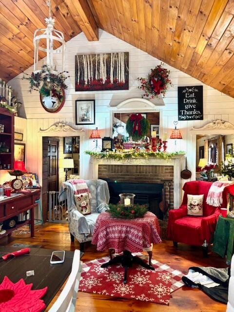 sitting room with a fireplace, wood-type flooring, vaulted ceiling with beams, and wooden walls