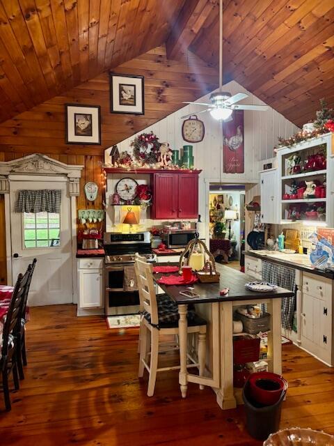 kitchen featuring appliances with stainless steel finishes, ceiling fan, white cabinets, dark hardwood / wood-style floors, and wood walls