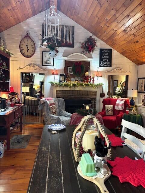 living room featuring wood ceiling, vaulted ceiling, a fireplace, hardwood / wood-style floors, and wood walls