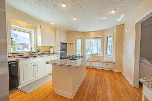 kitchen featuring white cabinets, sink, light hardwood / wood-style floors, a kitchen island, and stainless steel appliances