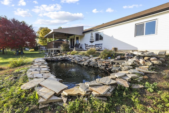 rear view of house featuring a wooden deck and a garden pond