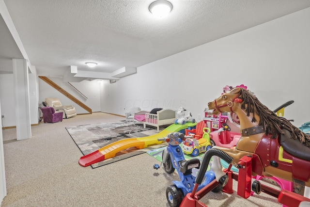 recreation room with carpet flooring and a textured ceiling