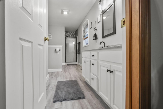 bathroom with vanity, a shower with shower door, and hardwood / wood-style flooring