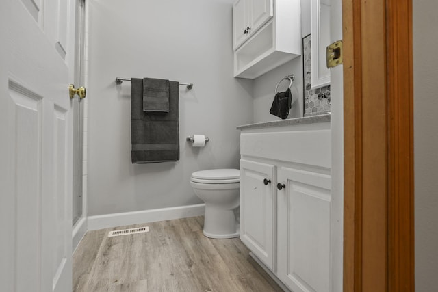 bathroom with wood-type flooring, vanity, toilet, and a shower with door