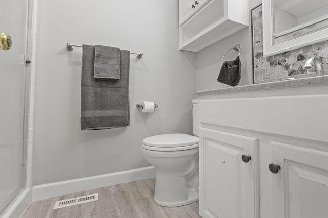 bathroom featuring hardwood / wood-style flooring, vanity, toilet, and backsplash