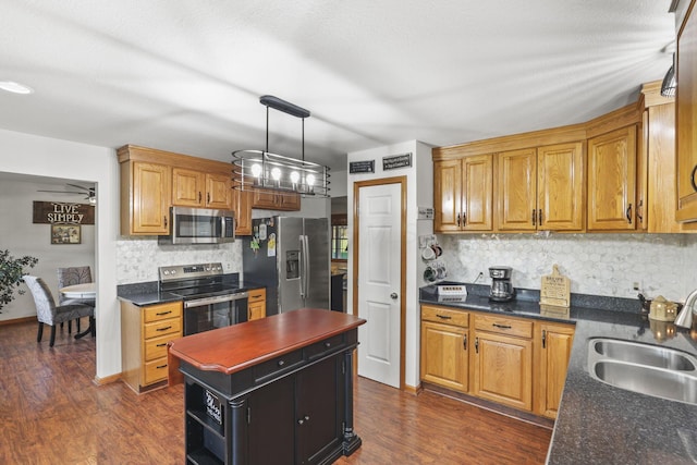 kitchen with ceiling fan, sink, dark wood-type flooring, backsplash, and appliances with stainless steel finishes