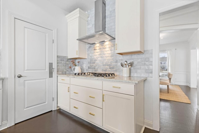 kitchen with stainless steel gas stovetop, tasteful backsplash, white cabinets, light stone counters, and wall chimney range hood