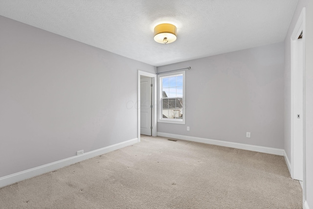 unfurnished room featuring light carpet and a textured ceiling