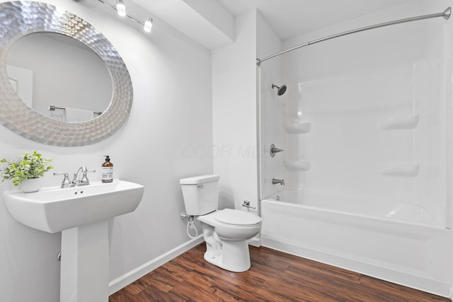 full bathroom with hardwood / wood-style flooring, sink, washtub / shower combination, and toilet