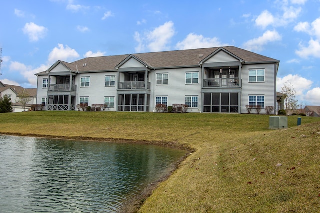 back of property with a lawn, a balcony, and a water view