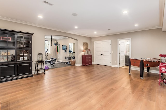 workout area with light hardwood / wood-style floors and ornamental molding