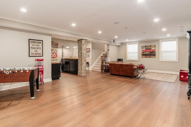 recreation room featuring light hardwood / wood-style floors, ornamental molding, and bar