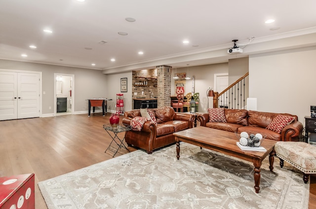 living room featuring bar, wood-type flooring, and ornamental molding