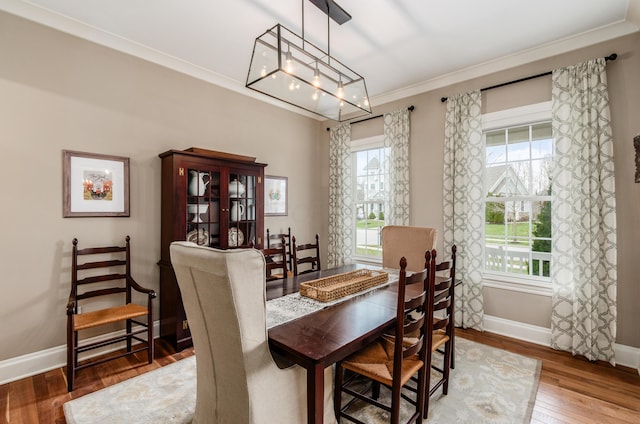 dining room with hardwood / wood-style flooring, crown molding, and a notable chandelier