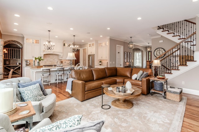 living room with light hardwood / wood-style flooring, a chandelier, and ornamental molding