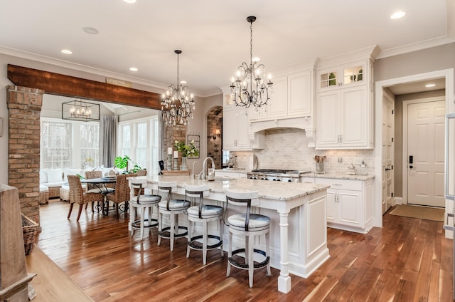 kitchen featuring a center island with sink, light stone countertops, white cabinetry, and dark wood-type flooring