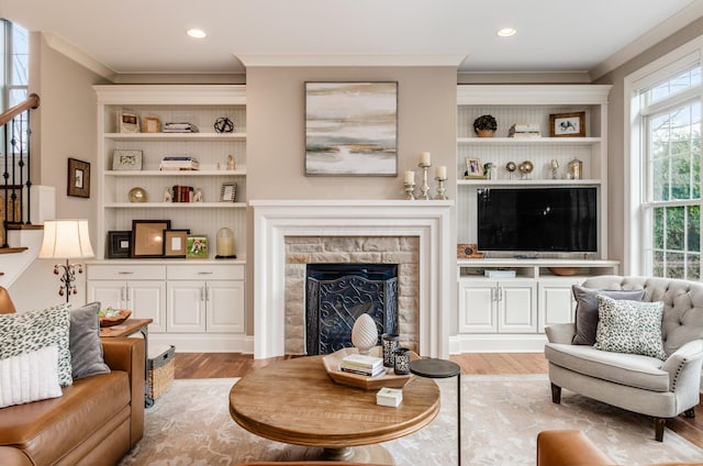 living room featuring a fireplace, light hardwood / wood-style floors, and ornamental molding