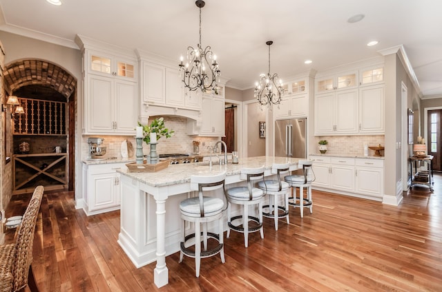 kitchen with white cabinetry, a kitchen island with sink, and high quality fridge