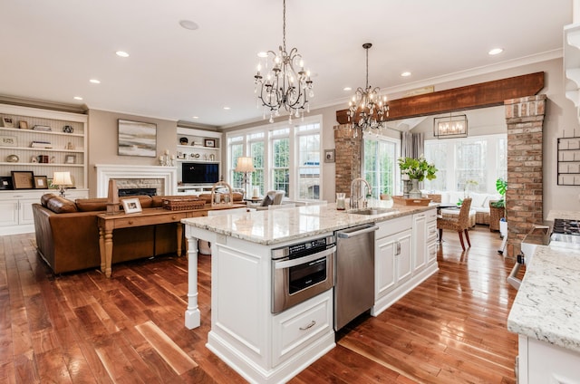 kitchen featuring light stone countertops, a center island with sink, white cabinets, and appliances with stainless steel finishes