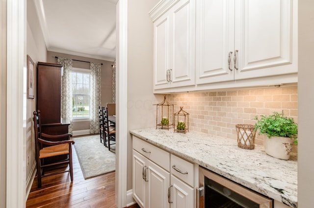 bar with ornamental molding, wine cooler, white cabinetry, and dark wood-type flooring